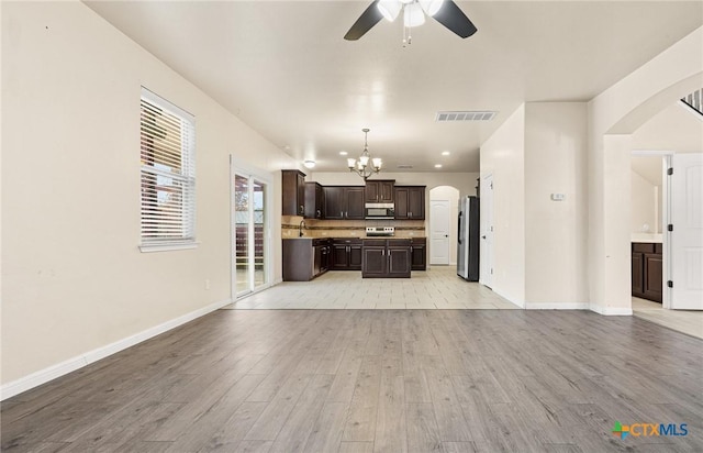 unfurnished living room with ceiling fan with notable chandelier, sink, and light hardwood / wood-style flooring