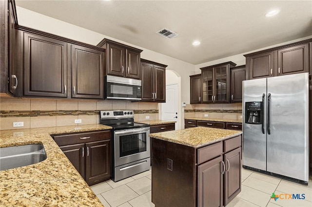 kitchen featuring backsplash, stainless steel appliances, and dark brown cabinetry