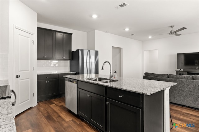 kitchen with black refrigerator, dark hardwood / wood-style flooring, sink, stainless steel dishwasher, and a kitchen island with sink