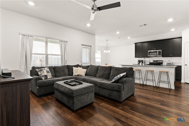 living room featuring dark hardwood / wood-style flooring, ceiling fan with notable chandelier, and plenty of natural light