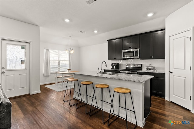 kitchen with a kitchen island with sink, stainless steel appliances, and dark hardwood / wood-style flooring