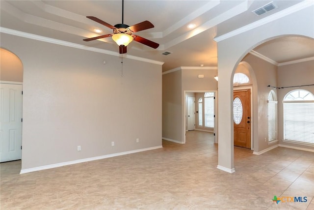 entryway featuring arched walkways, a tray ceiling, visible vents, and crown molding