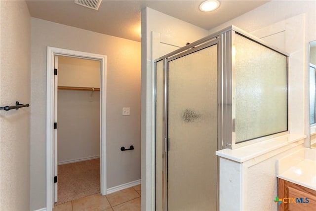 bathroom featuring a shower stall, visible vents, a walk in closet, and tile patterned floors