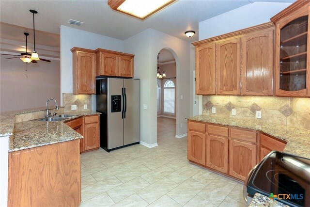 kitchen with arched walkways, electric stove, stainless steel fridge with ice dispenser, a peninsula, and a sink