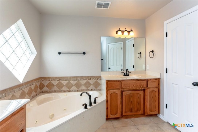 bathroom featuring tile patterned flooring, visible vents, a tub with jets, and vanity