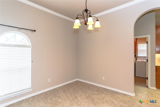 empty room with washer / dryer, plenty of natural light, arched walkways, and ornamental molding