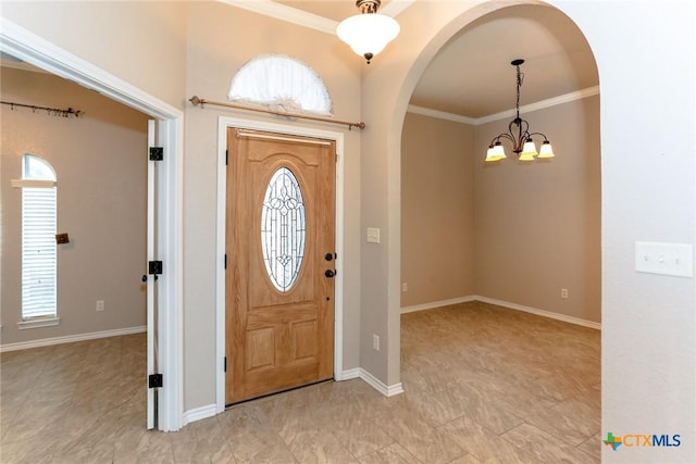 entrance foyer with ornamental molding, arched walkways, and a healthy amount of sunlight