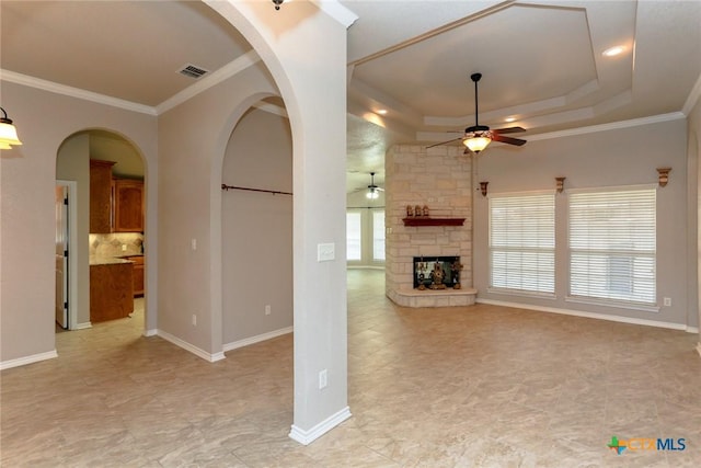 unfurnished living room featuring a stone fireplace, ornamental molding, visible vents, and a ceiling fan