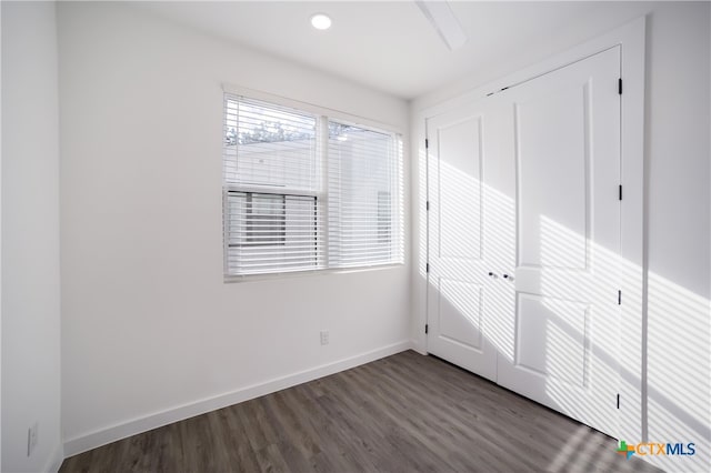 unfurnished bedroom featuring dark wood-type flooring and a closet