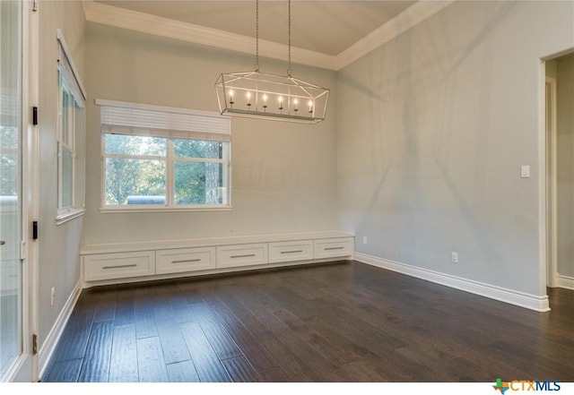 unfurnished dining area featuring dark wood-type flooring, ornamental molding, and a chandelier