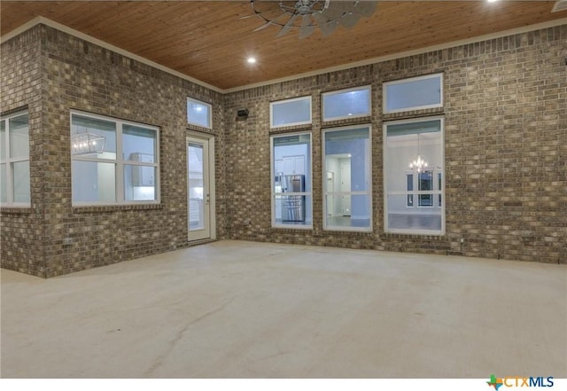 unfurnished room featuring brick wall, a notable chandelier, crown molding, and wood ceiling