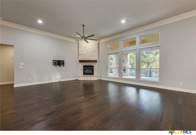 unfurnished living room featuring dark wood-type flooring, ceiling fan, crown molding, and a stone fireplace