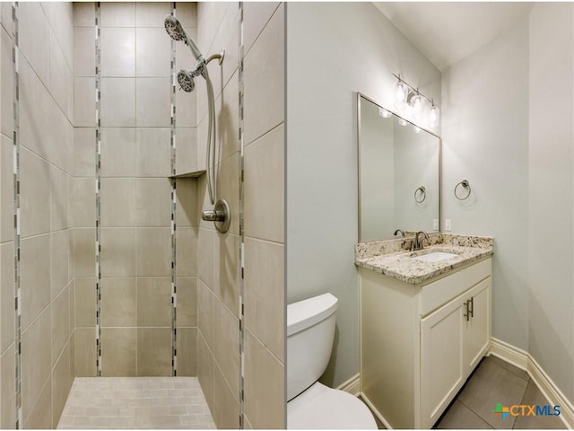 bathroom with toilet, a tile shower, tile patterned floors, and vanity