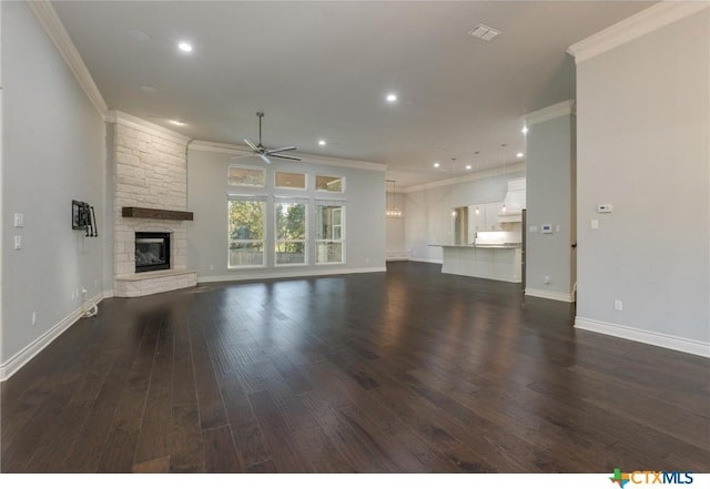 unfurnished living room with dark wood-type flooring, ceiling fan, ornamental molding, and a stone fireplace