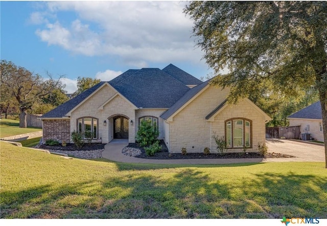 french provincial home with central air condition unit and a front lawn