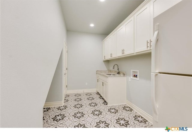 clothes washing area with sink, washer hookup, light tile patterned floors, and cabinets