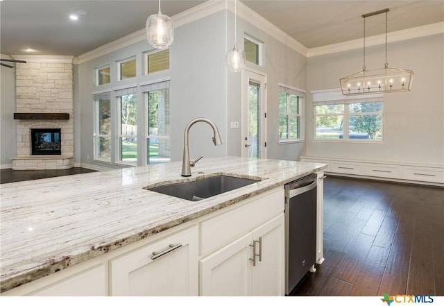 kitchen with sink, decorative light fixtures, white cabinets, stainless steel dishwasher, and light stone countertops