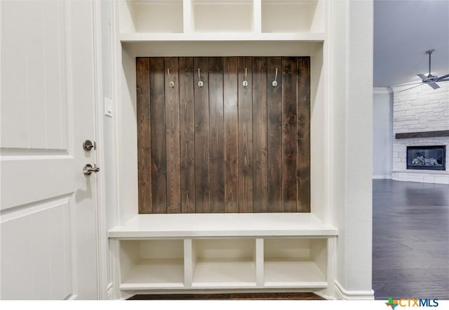 mudroom with ornamental molding, ceiling fan, and a stone fireplace