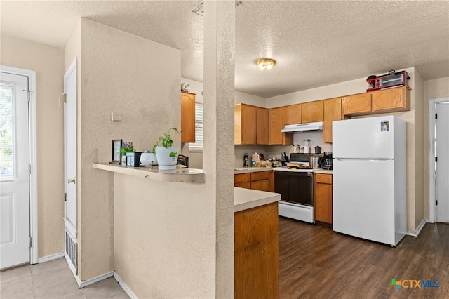 4509 Mattie Dr Unit A-D, Killeen, TX 76549 - kitchen with white appliances, under cabinet range hood, light countertops, a peninsula, and wood finished floors