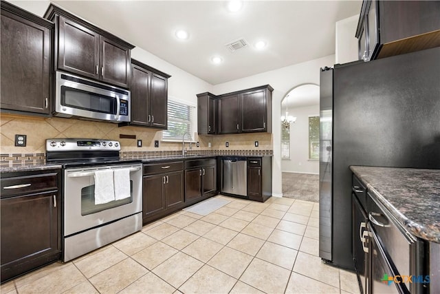 703 Curtis Dr, Killeen, TX 76542 - kitchen featuring appliances with stainless steel finishes, dark brown cabinets, backsplash, arched walkways, and light tile patterned floors