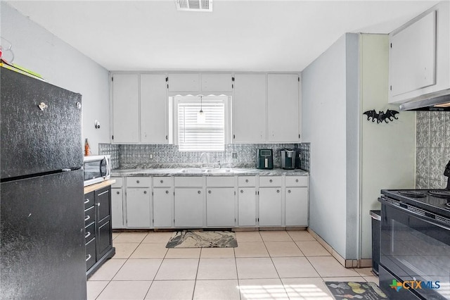 kitchen with light tile patterned flooring, sink, white cabinets, and black appliances