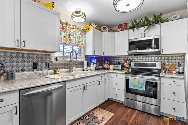 kitchen featuring white cabinets, appliances with stainless steel finishes, dark wood-type flooring, and sink