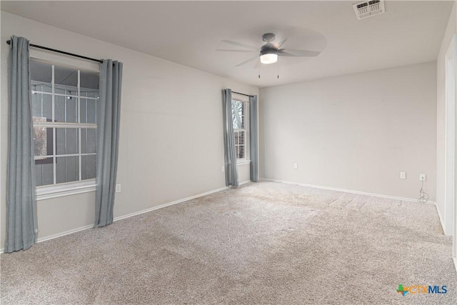 carpeted empty room with a ceiling fan, visible vents, and baseboards