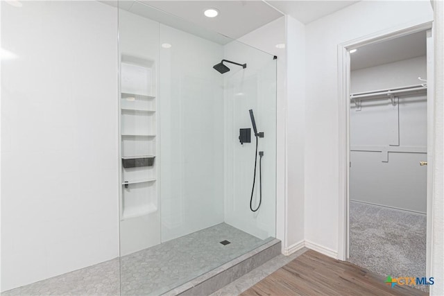 full bathroom with a spacious closet, walk in shower, and wood finished floors