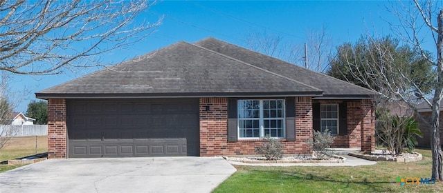 ranch-style house featuring a garage, fence, concrete driveway, and brick siding