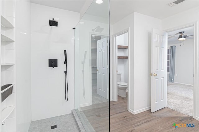 bathroom featuring ceiling fan, toilet, wood finished floors, visible vents, and walk in shower