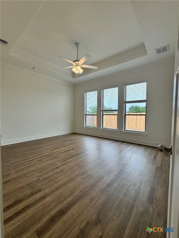 10826 Campsite Cv, Temple, TX 76502 - unfurnished room featuring a raised ceiling, ornamental molding, dark wood finished floors, baseboards, and ceiling fan