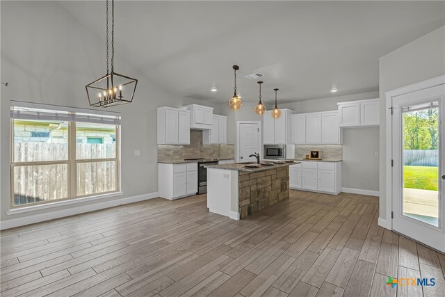 kitchen featuring light wood-type flooring, white cabinetry, a kitchen island with sink, and appliances with stainless steel finishes