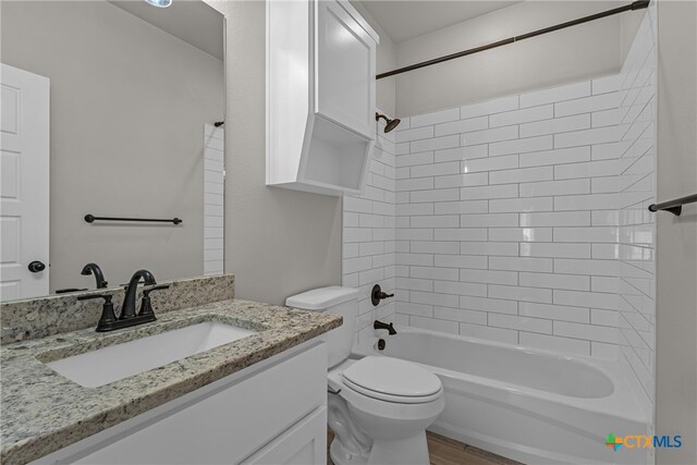 full bathroom featuring toilet, tiled shower / bath combo, vanity, and hardwood / wood-style flooring