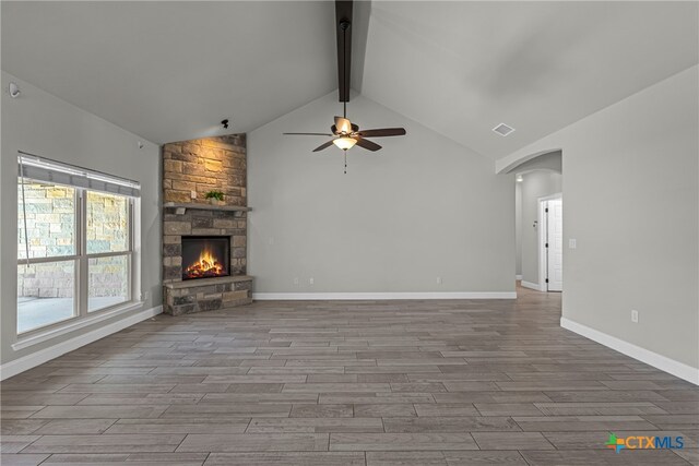 unfurnished living room with a fireplace, ceiling fan, beamed ceiling, and light wood-type flooring