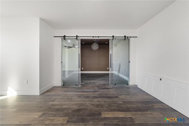 unfurnished room with dark wood-type flooring and a barn door