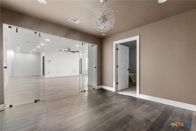 spare room featuring ceiling fan with notable chandelier and hardwood / wood-style flooring