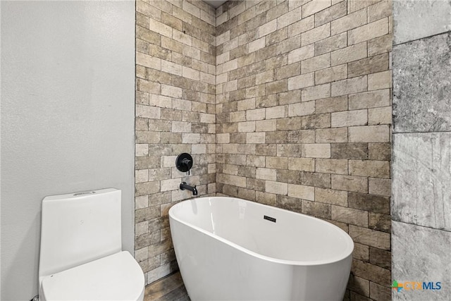 bathroom with a tub to relax in and toilet