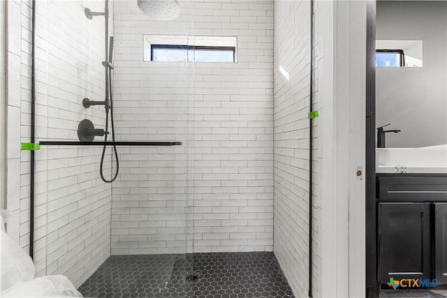 bathroom with a shower with shower door, vanity, and a healthy amount of sunlight