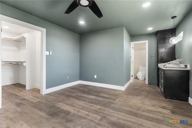 bedroom featuring a walk in closet, ensuite bath, dark hardwood / wood-style flooring, a closet, and ceiling fan