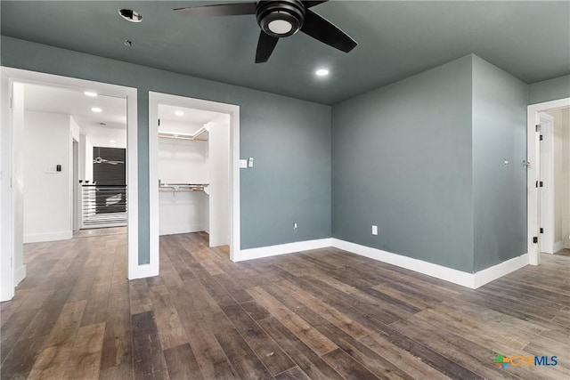 interior space with ceiling fan, a closet, a spacious closet, and dark hardwood / wood-style flooring