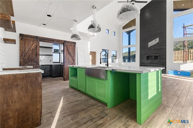 kitchen featuring a barn door, dark wood-type flooring, sink, and a center island with sink