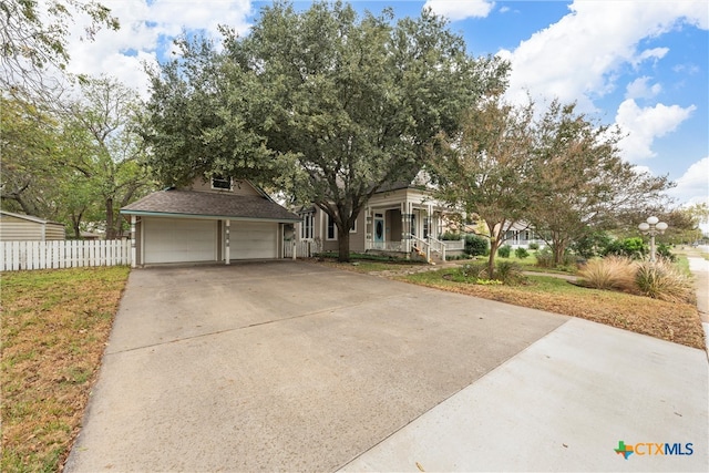 view of property hidden behind natural elements featuring covered porch and a garage