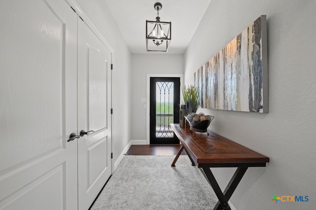 entryway with wood finished floors, baseboards, and a chandelier
