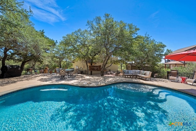view of swimming pool with an outdoor living space, fence, and a patio area