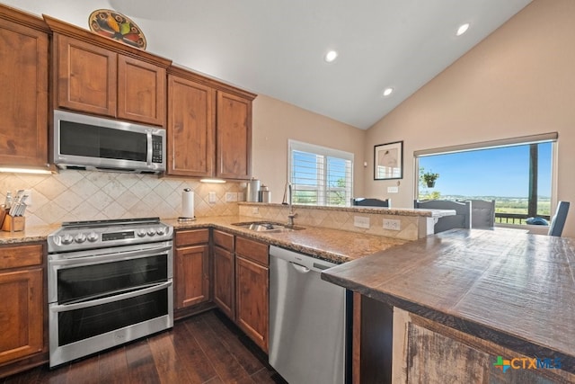 kitchen featuring stainless steel appliances, a sink, dark wood-style floors, backsplash, and recessed lighting