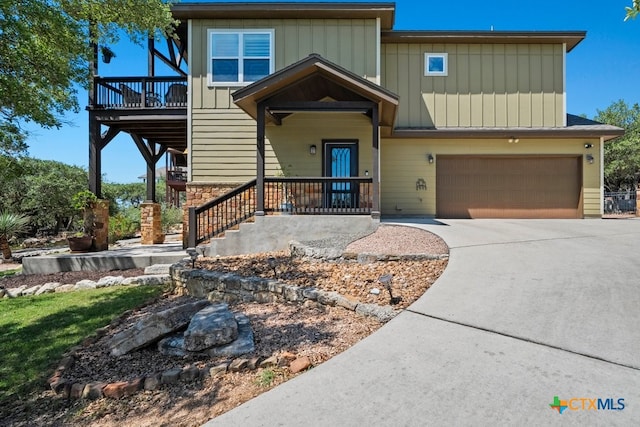 view of front of property with an attached garage, concrete driveway, stone siding, and covered porch