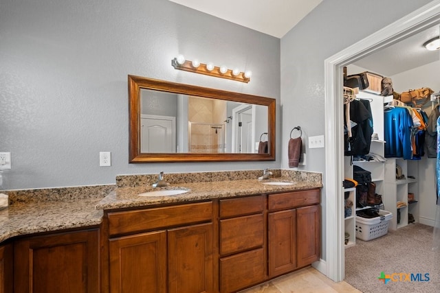 bathroom with a stall shower, a walk in closet, and double vanity