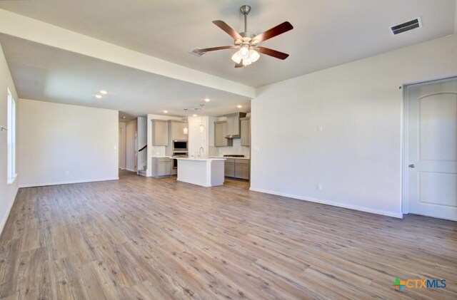 unfurnished living room with hardwood / wood-style flooring, ceiling fan, and sink