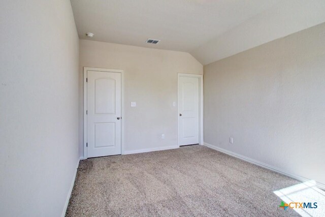 unfurnished bedroom featuring lofted ceiling and carpet floors