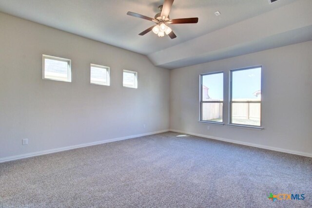 carpeted empty room with vaulted ceiling, plenty of natural light, and ceiling fan